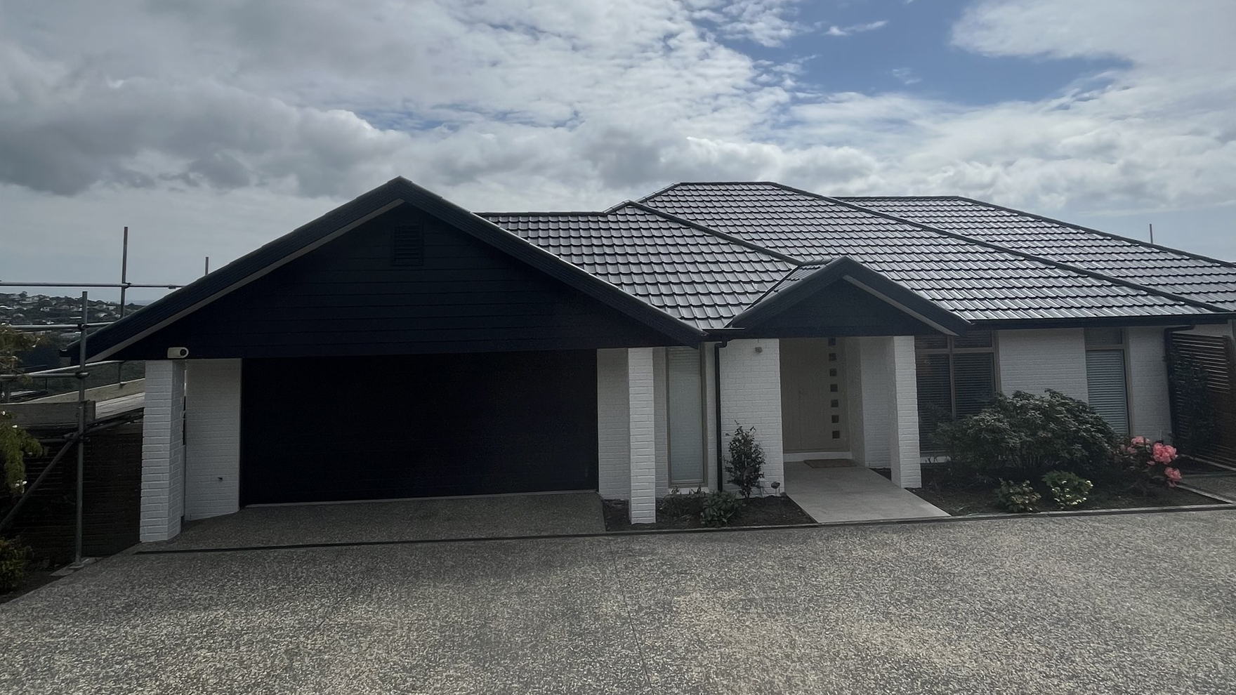 Dark grey painted concrete tile roof on a modern Christchurch house, seen from the street
