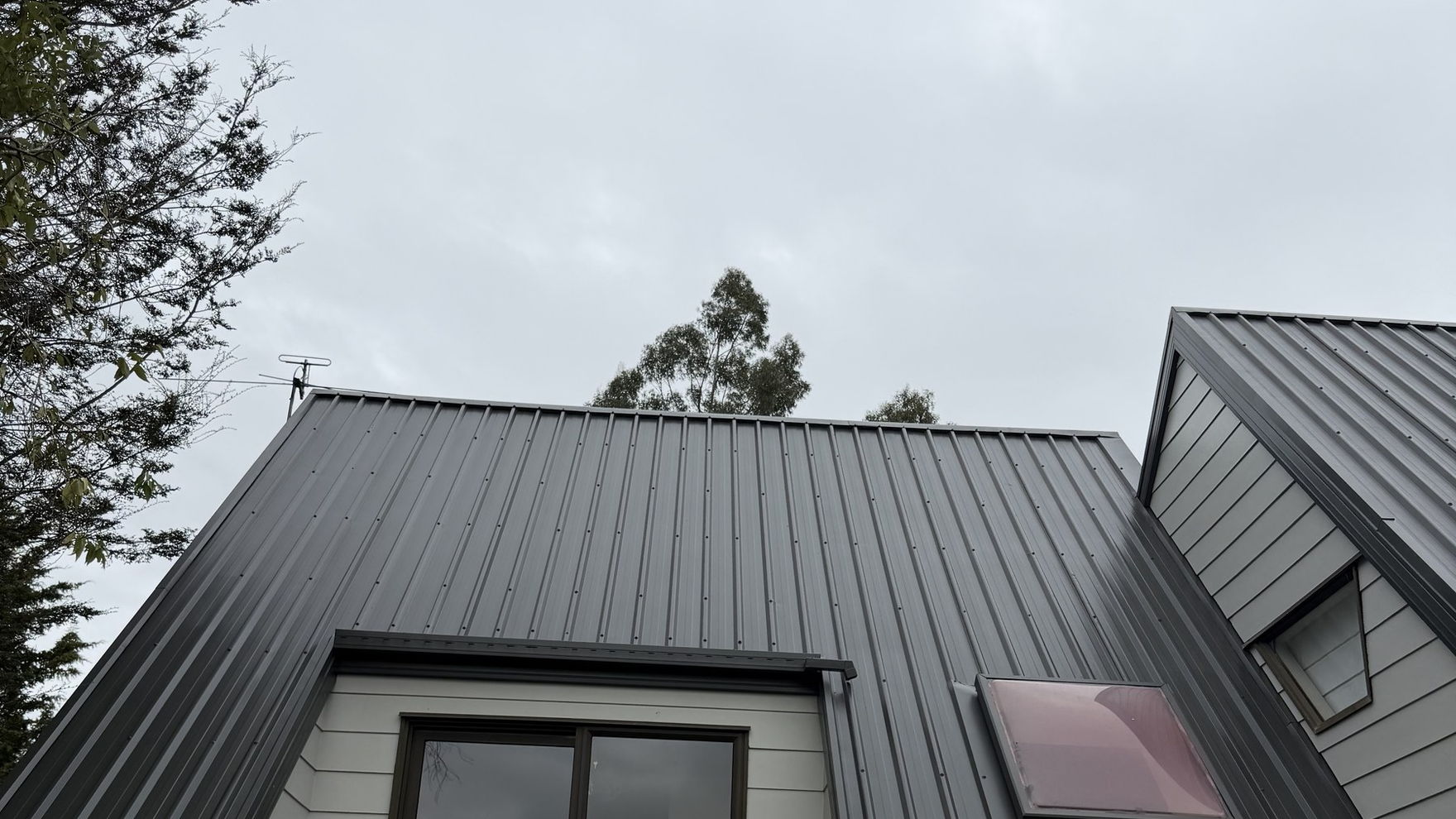 Two storey Kaiapoi house with its long-run metal roof freshly spray painted charcoal, skylight and dormer window below